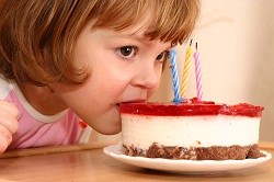 A THREE YEAR OLD GIRL EATING HER BIRTHDAY CAKE