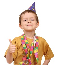 young boy in a party hat smiling with his thumb up