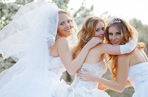 three brides walking arm in arm and looking behind them having a good time