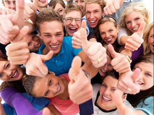 large group of teenagers smiling while holding a thumbs up playing a game