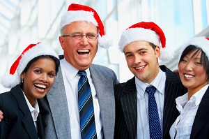 Adults in Santa hats laughing an office Christmas party