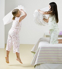 two little girls having a pillow fight at a slumber party