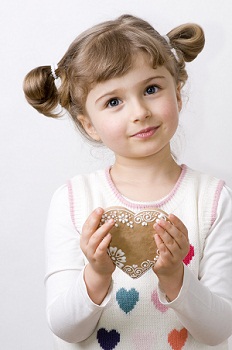 young girl holding a heart shaped cookie wearing a sweater with hearts on it for Valentines game