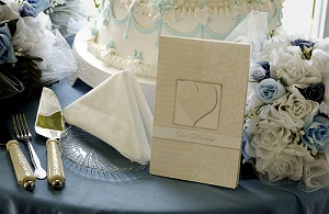 Wedding cake on table set for guests at a bridal shower with a place setting next to a wedding invitation.