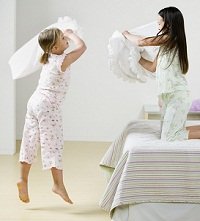 two little girls having a pillow fight at a slumber party